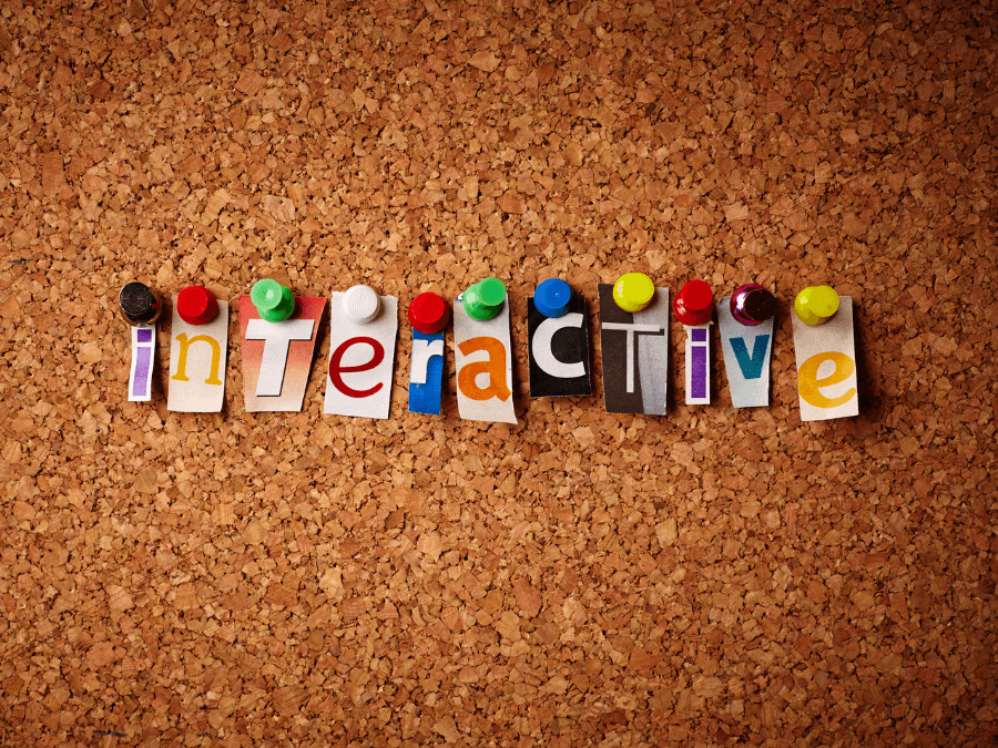 La palabra «interactive» formada con letras recortadas y clavadas en un tablero de corcho.